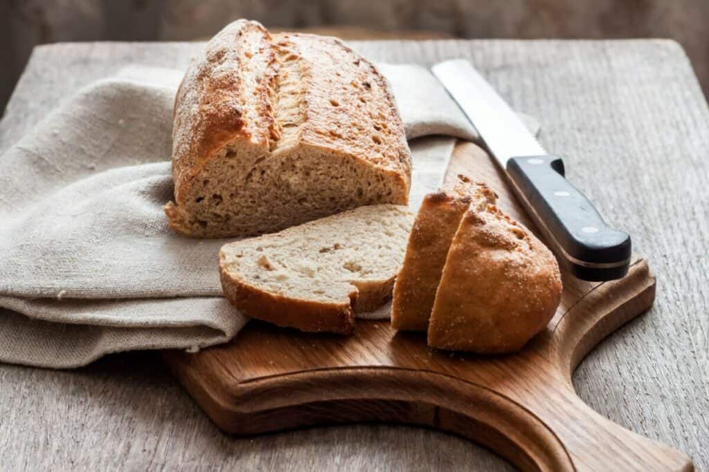Homemade bread and a knife on a wooden cutting board.